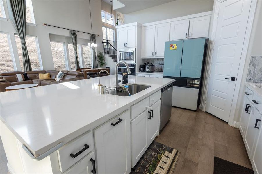 Kitchen with white cabinetry, appliances with stainless steel finishes, open floor plan, and a kitchen island with sink