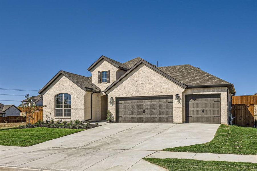 French provincial home featuring a garage and a front lawn