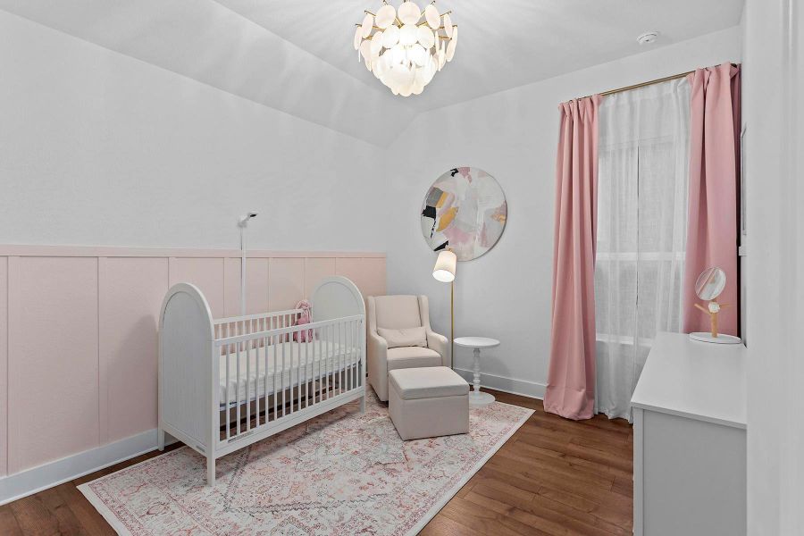 Bedroom with a nursery area, hardwood / wood-style floors, lofted ceiling, and a chandelier