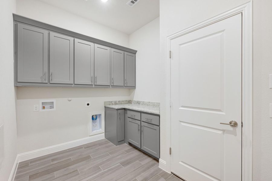 Laundry room with gray cabinets, granite countertop, washer hookups, and light wood-look tile floor Laundry room with gray cabinets, granite countertop, washer hookups, and light wood-look tile floor