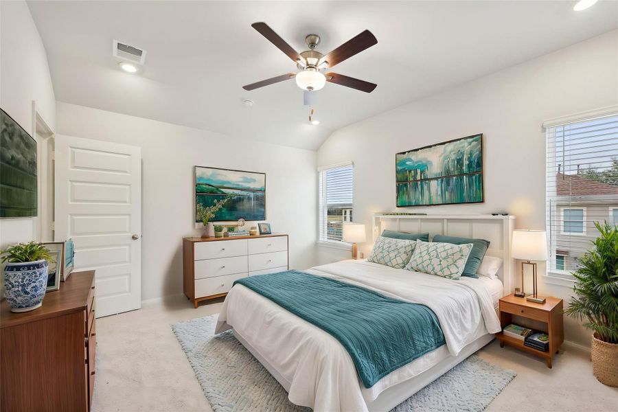 This spacious bedroom receives abundant natural light from large windows, creating a warm and inviting atmosphere.
