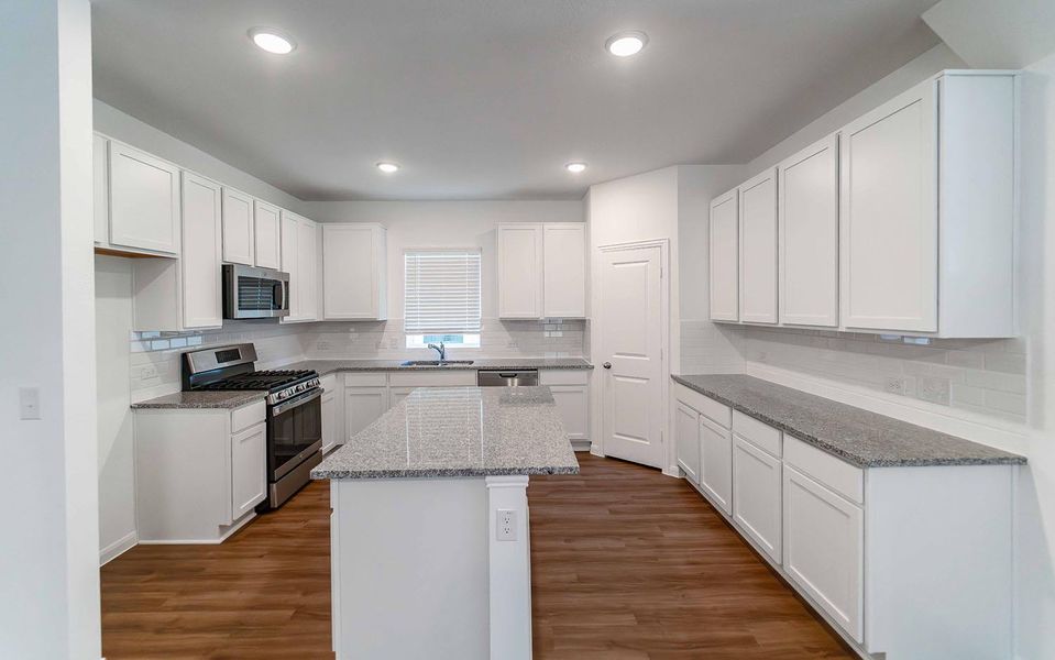 Kitchen featuring stainless steel appliances, dark wood-style flooring, white cabinetry, and recessed lighting Kitchen featuring stainless steel appliances, dark wood-style flooring, white cabinetry, and recessed lighting