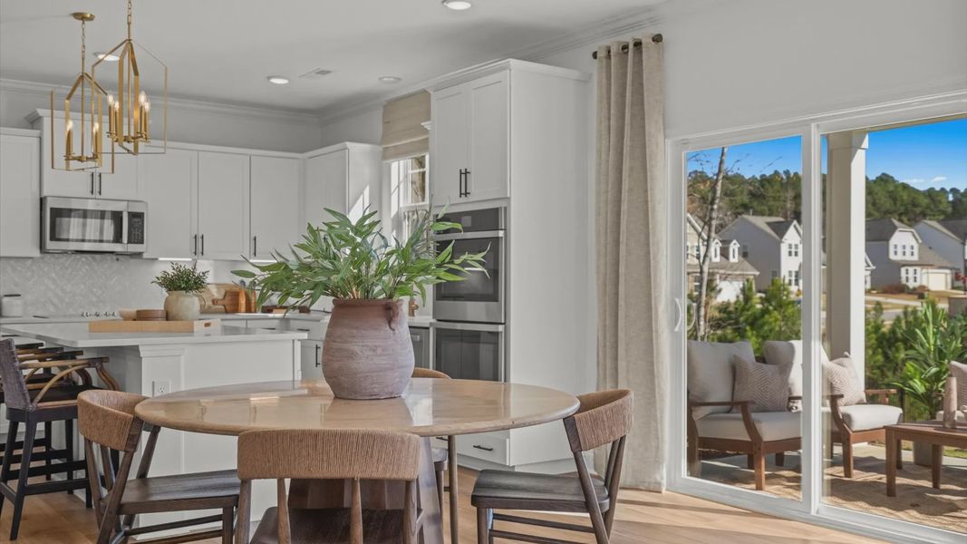 Wynwood home plan open concept breakfast/dining area and kitchen with island overlooking the back patio Wynwood home plan open concept breakfast/dining area and kitchen with island overlooking the back patio