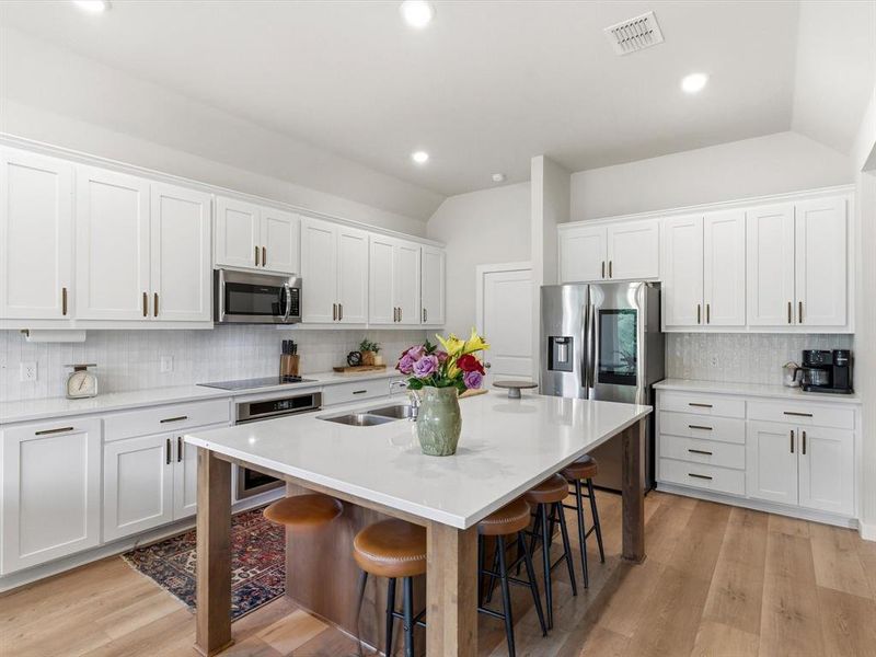 Farmhouse-inspired kitchen with ample cabinetry, generous counter space, and open sightlines to living area.