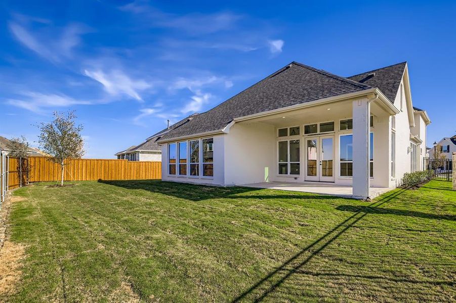 Rear view of property featuring a fenced backyard, stucco siding, a patio, a shingled roof, and french doors Rear view of property featuring a fenced backyard, stucco siding, a patio, a shingled roof, and french doors