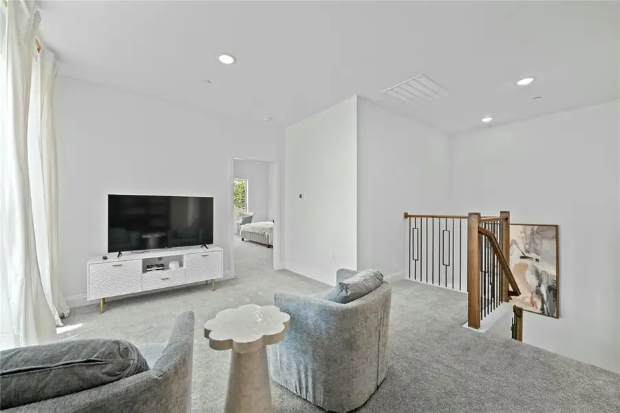 Carpeted living area with recessed lighting and baseboards