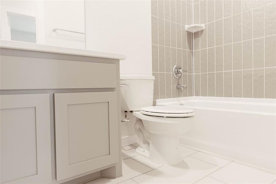 Full bathroom featuring tile patterned flooring, tiled shower / bath combo, toilet, and vanity