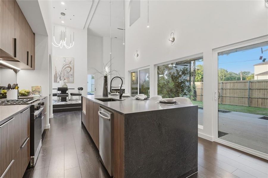 Modern kitchen featuring a dark stone-finish island with integrated sink, wood-finish cabinetry, stainless steel appliances, and dark wood-finish flooring