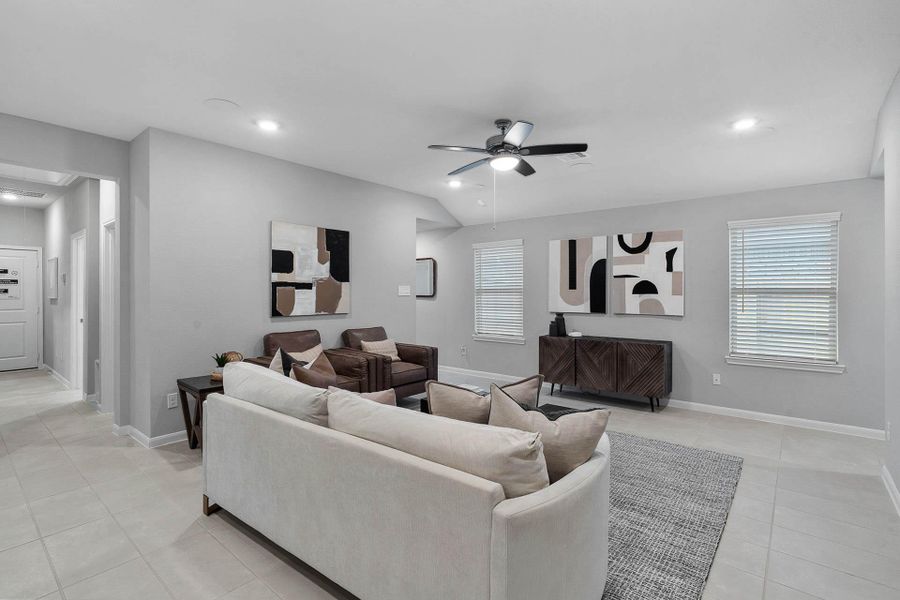 Enjoy a light-filled family room with two large windows featuring clean white blinds, complemented by a modern ceiling fan to keep the space cool and comfortable year-round.