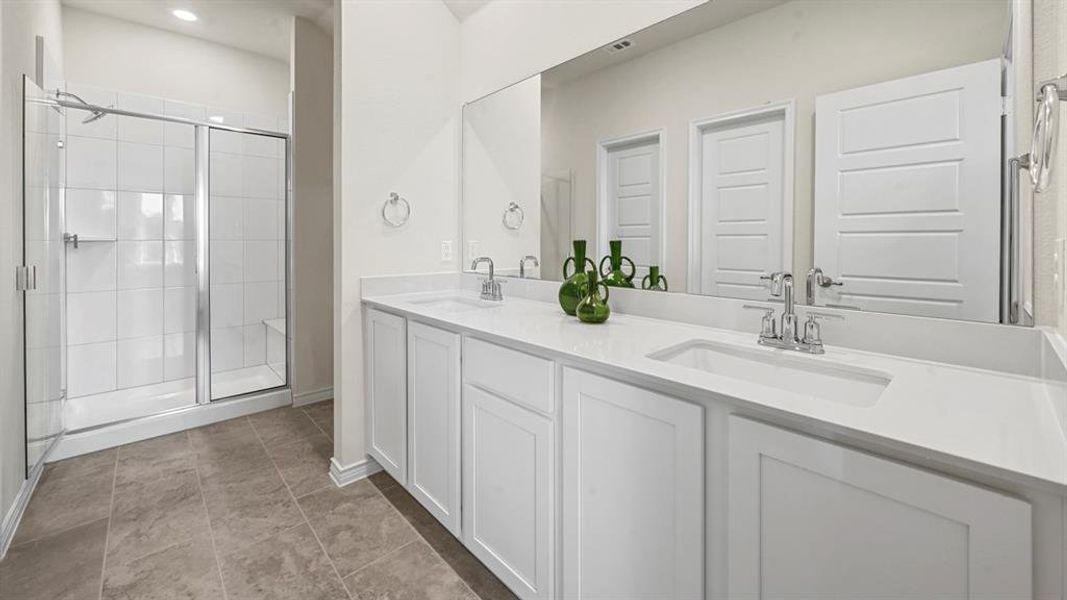 Bathroom with double vanity, a stall shower, and light tile patterned floors