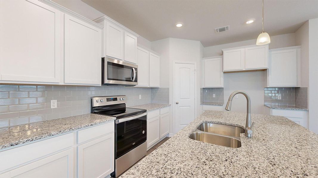 Kitchen with stainless steel appliances, white cabinets, pendant lighting, light stone countertops, and backsplash