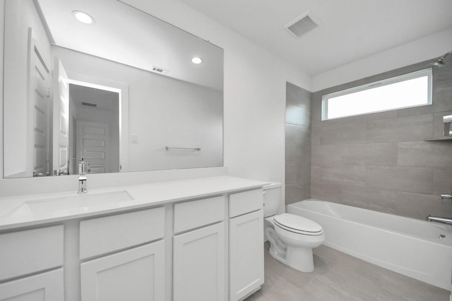 Secondary bath features tile flooring, bath/shower combo with tile surround, light stained wood cabinets, beautiful light countertop. Sample photo of completed home with similar floor plan. Actual colors and selections may vary. Secondary bath features tile flooring, bath/shower combo with tile surround, light stained wood cabinets, beautiful light countertop. Sample photo of completed home with similar floor plan. Actual colors and selections may vary.