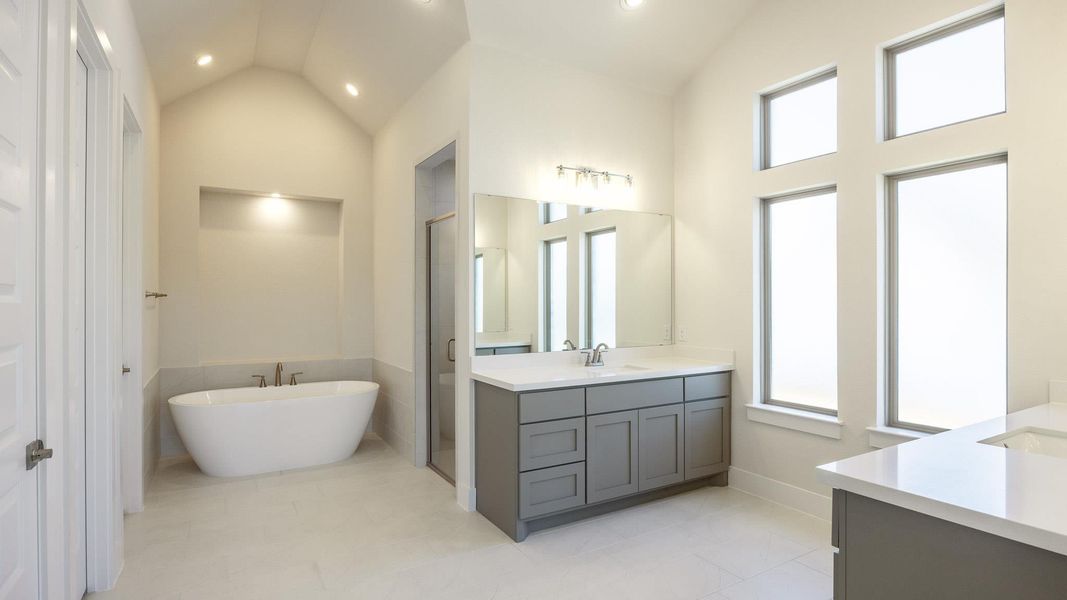Bathroom featuring vanity, a stall shower, a freestanding tub, and lofted ceiling Bathroom featuring vanity, a stall shower, a freestanding tub, and lofted ceiling