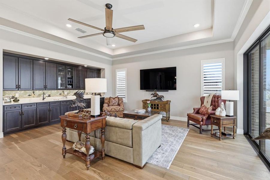 Grand Great Room anchored by an Impressive Built-in Bar designed for Effortless Entertaining. A Wall of Three-Panel Sliding Glass Doors opens to the Covered Outdoor Living Pavilion showcasing Panoramic Golf Course and Territorial Views.
