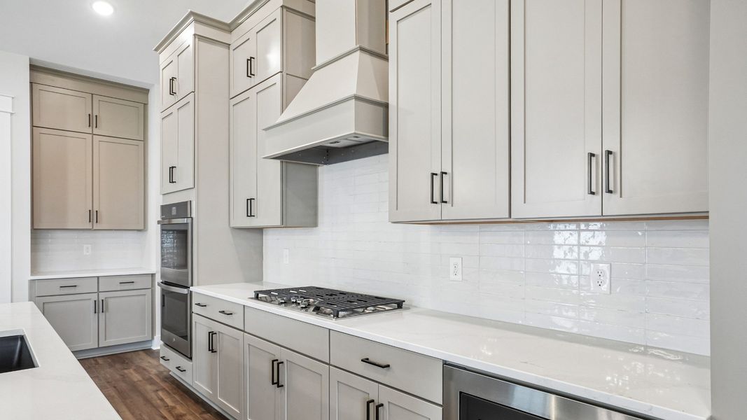 Kitchen with ceiling-height cabinetry, quartz countertops and gas range