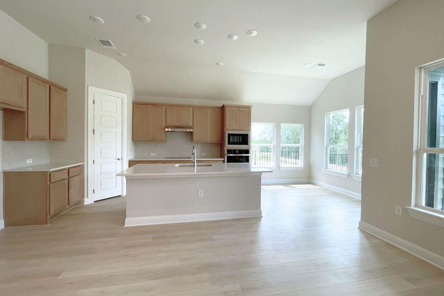 A well-lit kitchen with a central island and contemporary light wood cabinetry offers modern living.