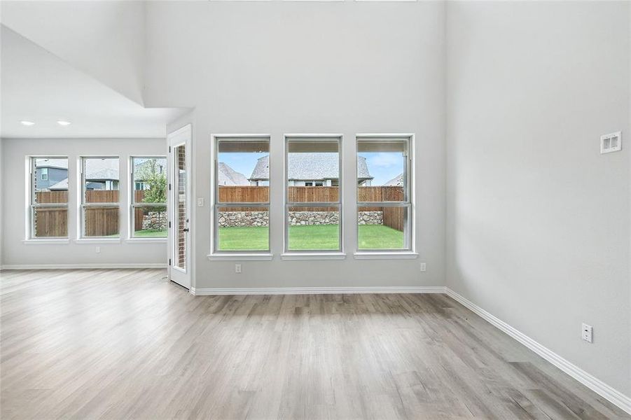 Unfurnished living room featuring wood finished floors, healthy amount of natural light, and a towering ceiling Unfurnished living room featuring wood finished floors, healthy amount of natural light, and a towering ceiling
