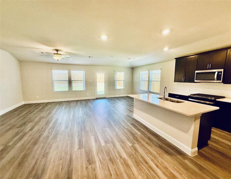 Spacious open-concept living area featuring wood-finish flooring, recessed lighting, and a ceiling fan Spacious open-concept living area featuring wood-finish flooring, recessed lighting, and a ceiling fan