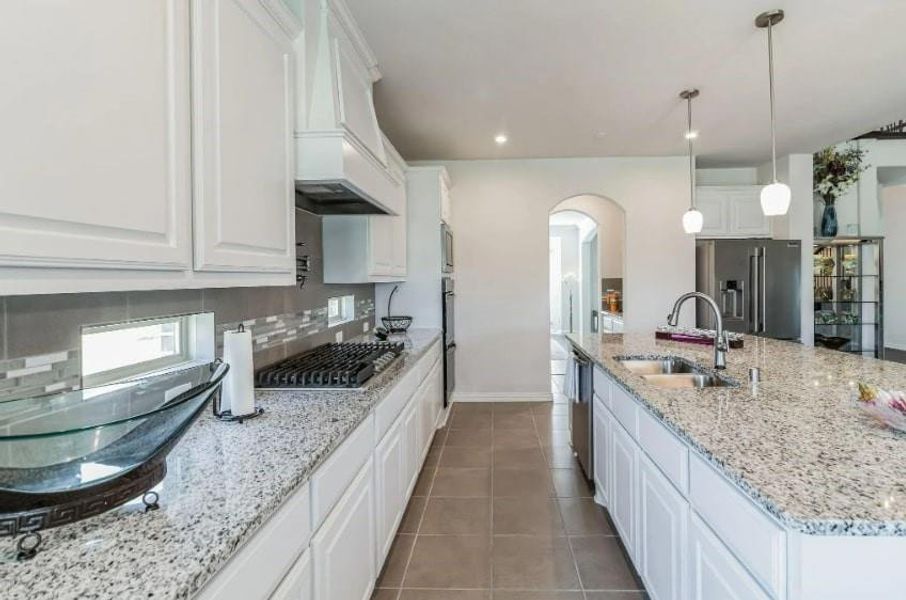 Kitchen featuring tile patterned flooring, stainless steel appliances, sink, decorative backsplash, and white cabinetry