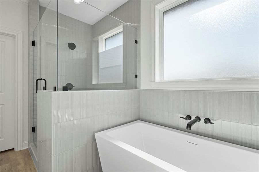 Full bath featuring a freestanding tub, a shower stall, and wood finished floors Full bath featuring a freestanding tub, a shower stall, and wood finished floors