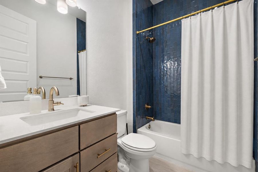 A well-appointed bath features a deep blue tiled shower and a modern vanity. A well-appointed bath features a deep blue tiled shower and a modern vanity.