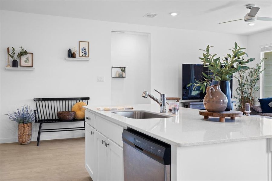 Kitchen featuring SS dishwasher, a ceiling fan, white cabinetry, light stone countertops, and light LVP finished floors Kitchen featuring SS dishwasher, a ceiling fan, white cabinetry, light stone countertops, and light LVP finished floors