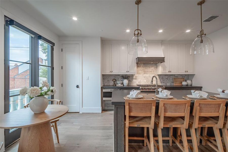 Kitchen with white cabinets, light hardwood / wood-style floors, and decorative light fixtures