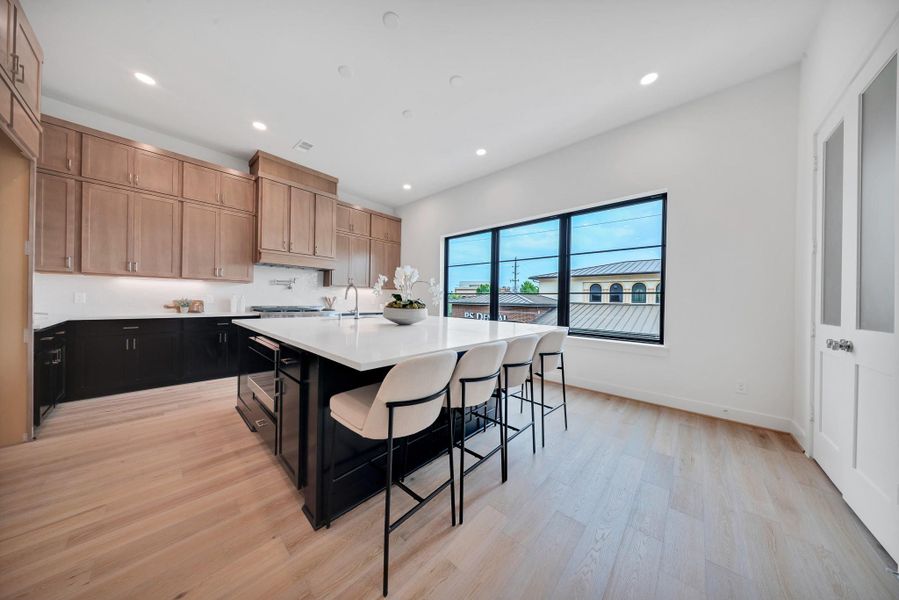 Modern kitchen with a spacious layout, featuring light wood flooring, sleek cabinets, and a large island with seating. Modern kitchen with a spacious layout, featuring light wood flooring, sleek cabinets, and a large island with seating.