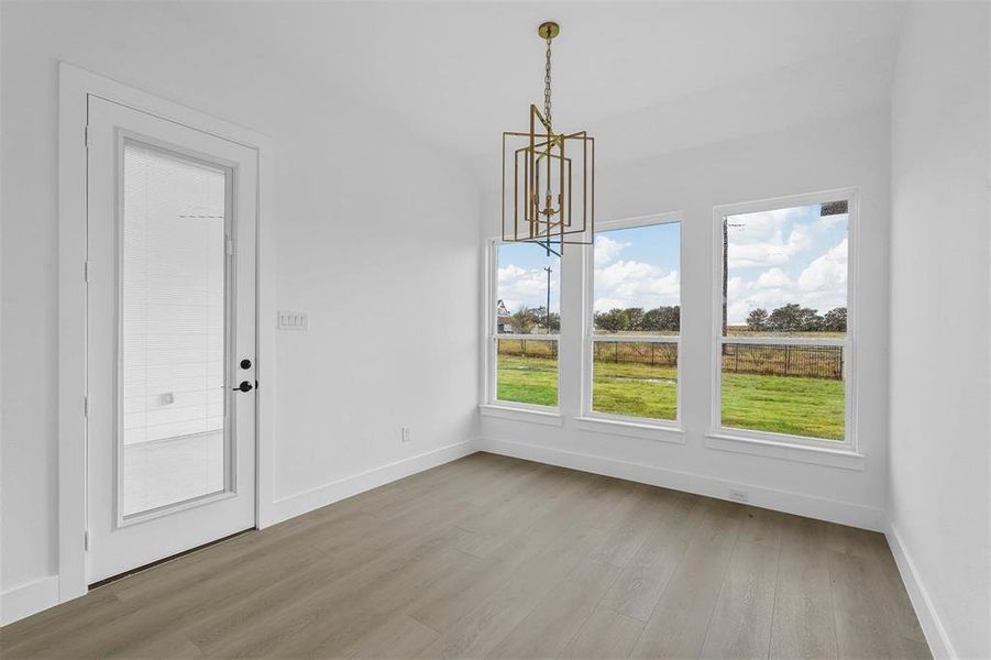 Unfurnished dining area featuring a chandelier and light wood-style floors Unfurnished dining area featuring a chandelier and light wood-style floors