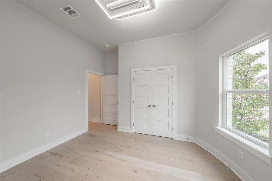 Unfurnished bedroom with cooling unit, light wood-style flooring, and a closet