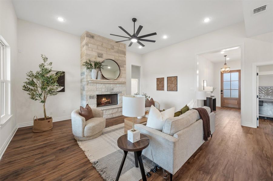 Living room featuring dark wood-style flooring, a stone fireplace, recessed lighting, and a ceiling fan Living room featuring dark wood-style flooring, a stone fireplace, recessed lighting, and a ceiling fan