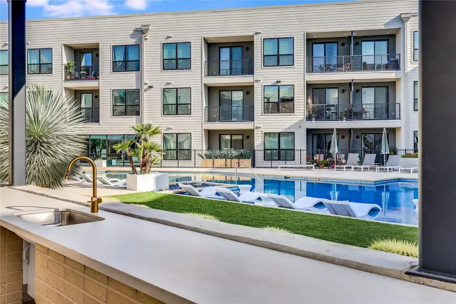 An inviting community pool with loungers and an outdoor kitchen!