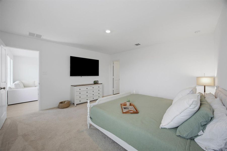 Plush carpeting and recessed lighting create a comfortable, minimalist retreat in this bedroom.