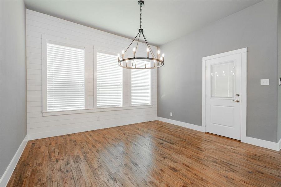 Unfurnished dining area featuring an inviting chandelier, baseboards, and wood finished floors Unfurnished dining area featuring an inviting chandelier, baseboards, and wood finished floors