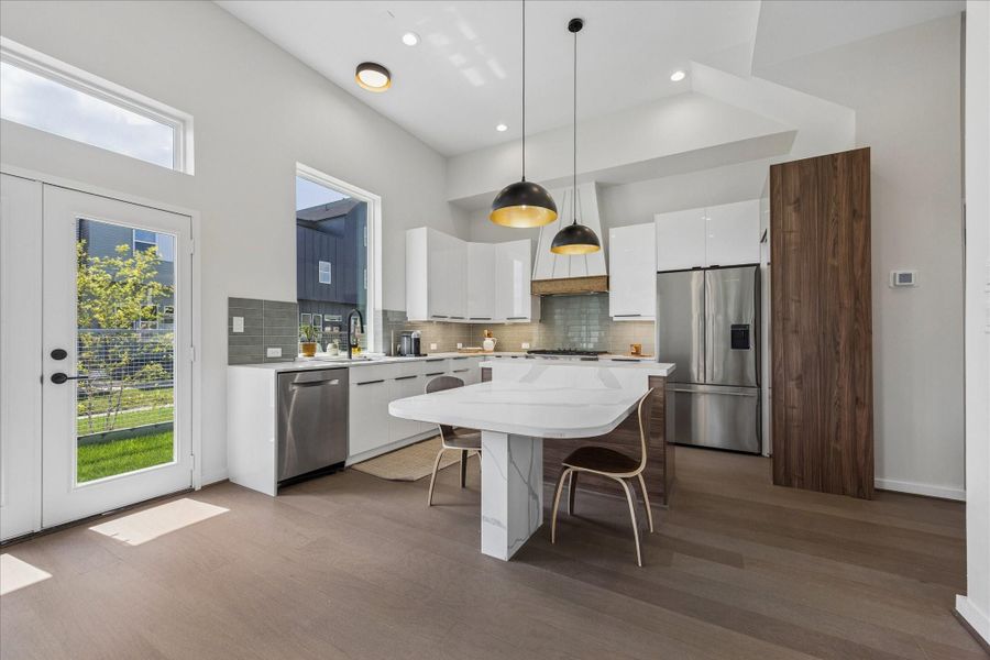 Designer kitchen featuring a waterfall island, sleek flat-panel cabinetry, and modern finishes throughout. Designer kitchen featuring a waterfall island, sleek flat-panel cabinetry, and modern finishes throughout.