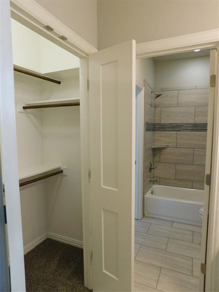 Jack & Jill Bathroom featuring tiled shower / bath combo and toilet