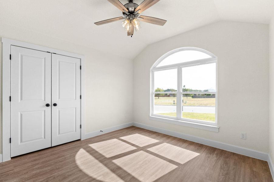Unfurnished bedroom with lofted ceiling, light wood-style flooring, a closet, and ceiling fan
