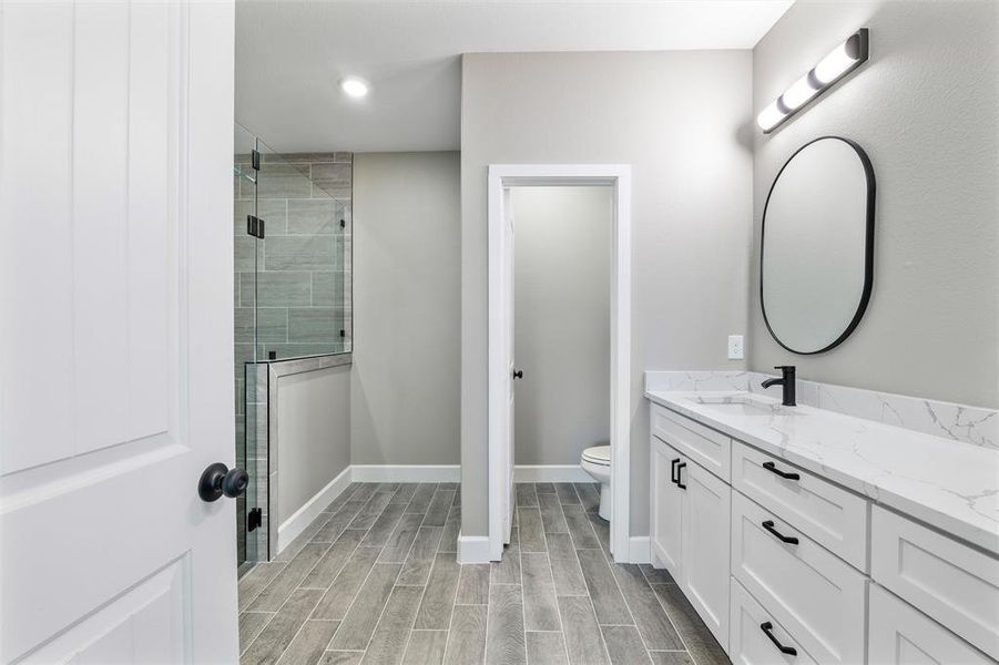 Bathroom with vanity, a shower with door, and toilet