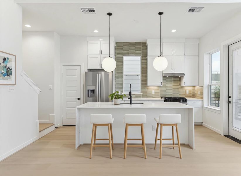 Large waterfall-edge island anchors the kitchen, offering generous workspace and seating. *Virtually staged*