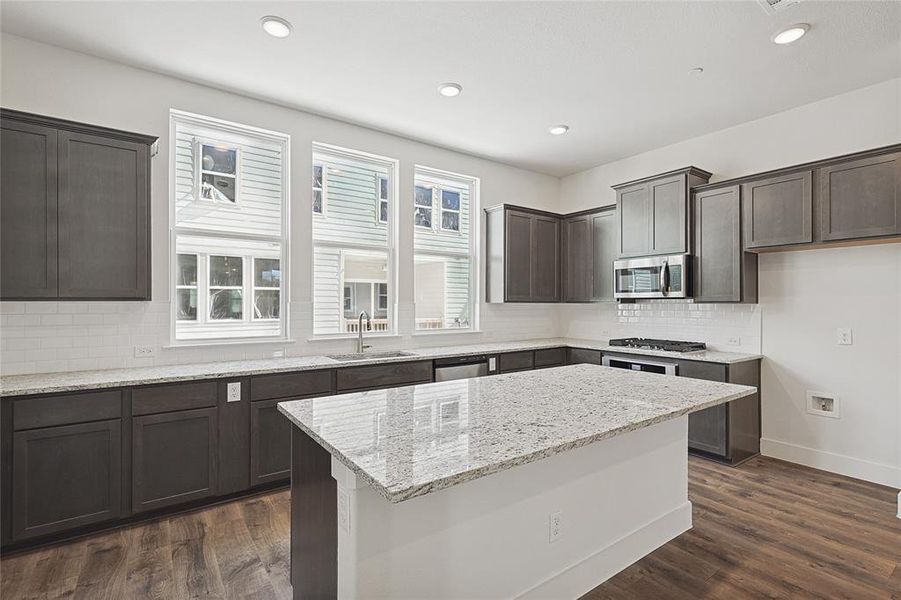 Kitchen featuring light stone countertops, dark hardwood / wood-style flooring, stainless steel appliances, and sink