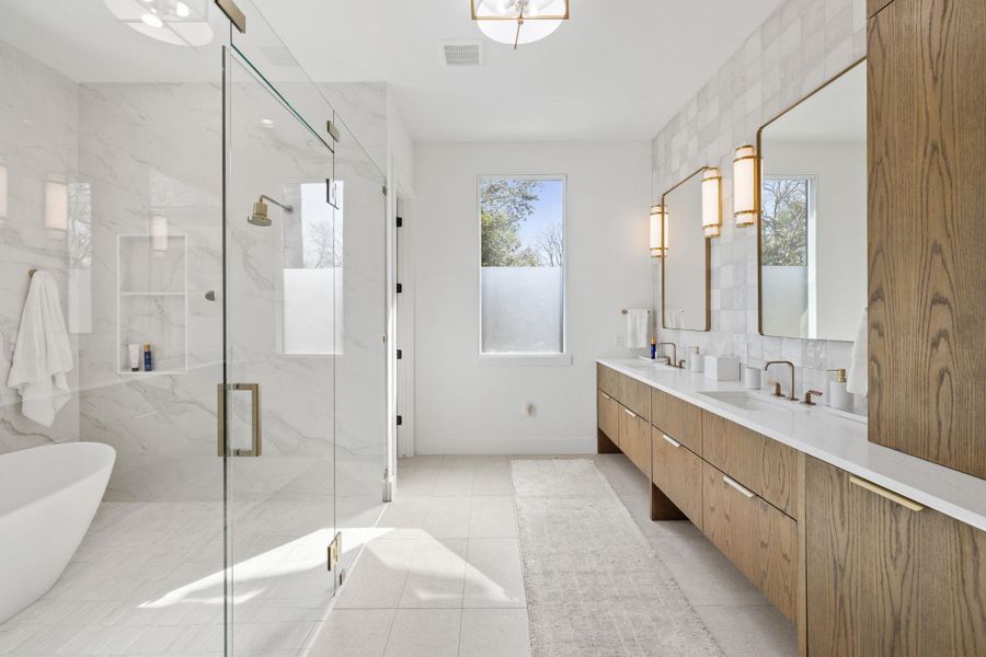Bathroom featuring double vanity, a marble finish shower, a soaking tub, and light tile patterned floors