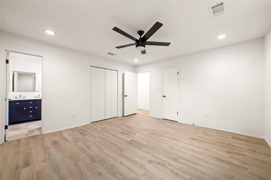 Unfurnished bedroom featuring light wood-style flooring, connected bathroom, visible vents, and baseboards Unfurnished bedroom featuring light wood-style flooring, connected bathroom, visible vents, and baseboards
