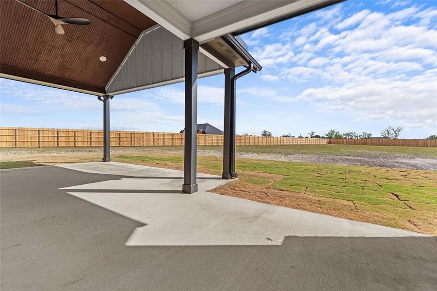 Fenced backyard with a ceiling fan and a patio area