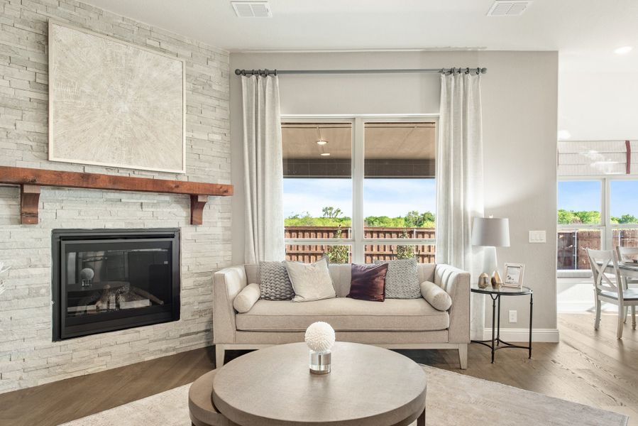 Living room with stone fireplace, wood mantel, gray sofa, and hardwood floors
