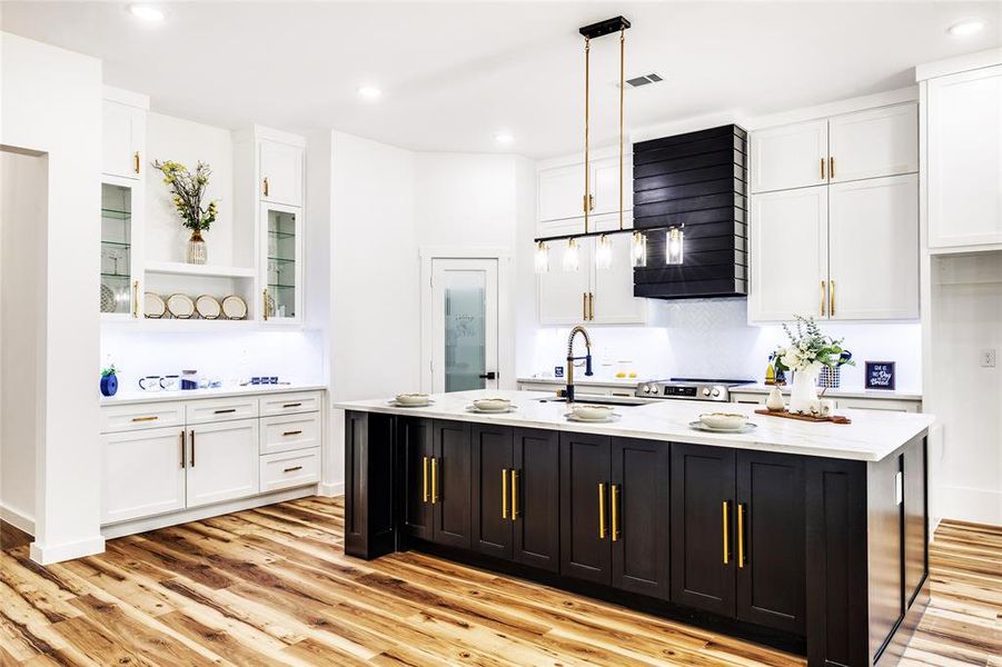 Kitchen featuring white cabinets, dark cabinetry, glass insert cabinets, light wood-style flooring, and recessed lighting