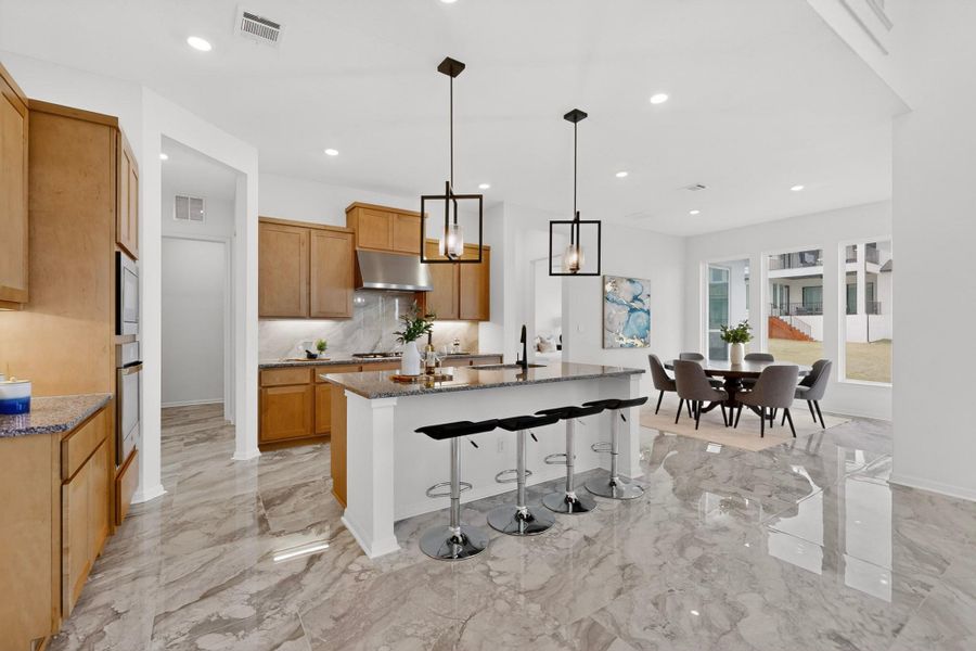 Kitchen featuring a central island with bar seating, stainless steel appliances, light wood cabinetry, and a light-toned patterned floor
