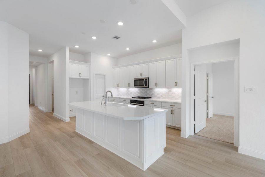 The large kitchen island with quartz countertops offers ample prep space and additional seating.