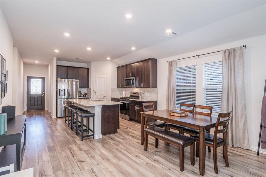 Kitchen with a center island with sink, visible vents, a breakfast bar, stainless steel appliances, and a sink