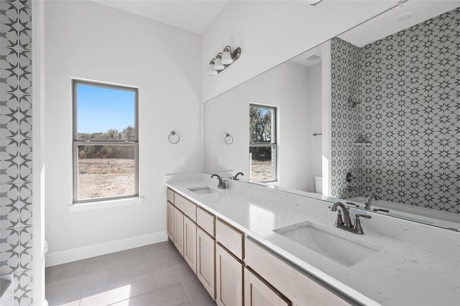 Full bathroom featuring double vanity and light tile patterned floors Full bathroom featuring double vanity and light tile patterned floors