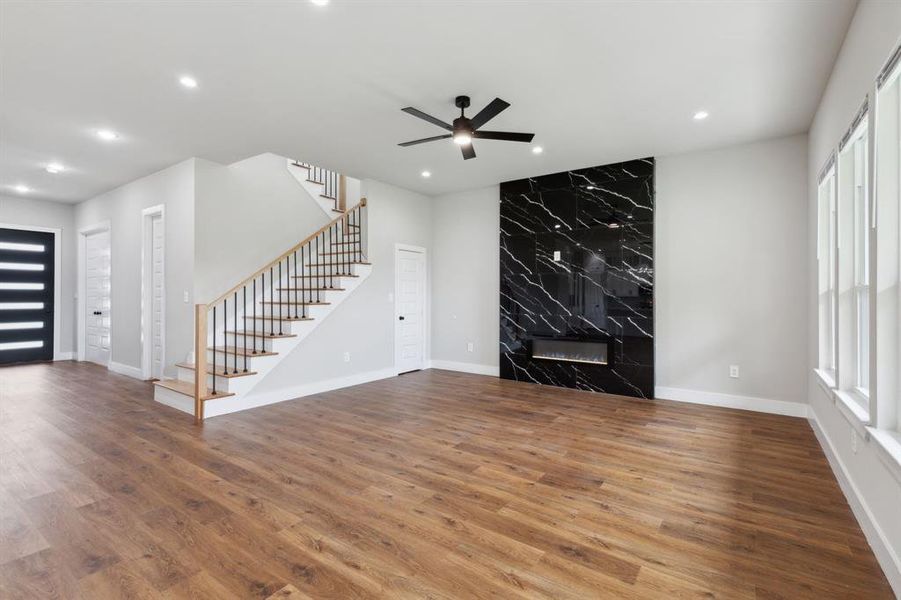 Unfurnished living room with ceiling fan, a high end fireplace, and hardwood / wood-style floors